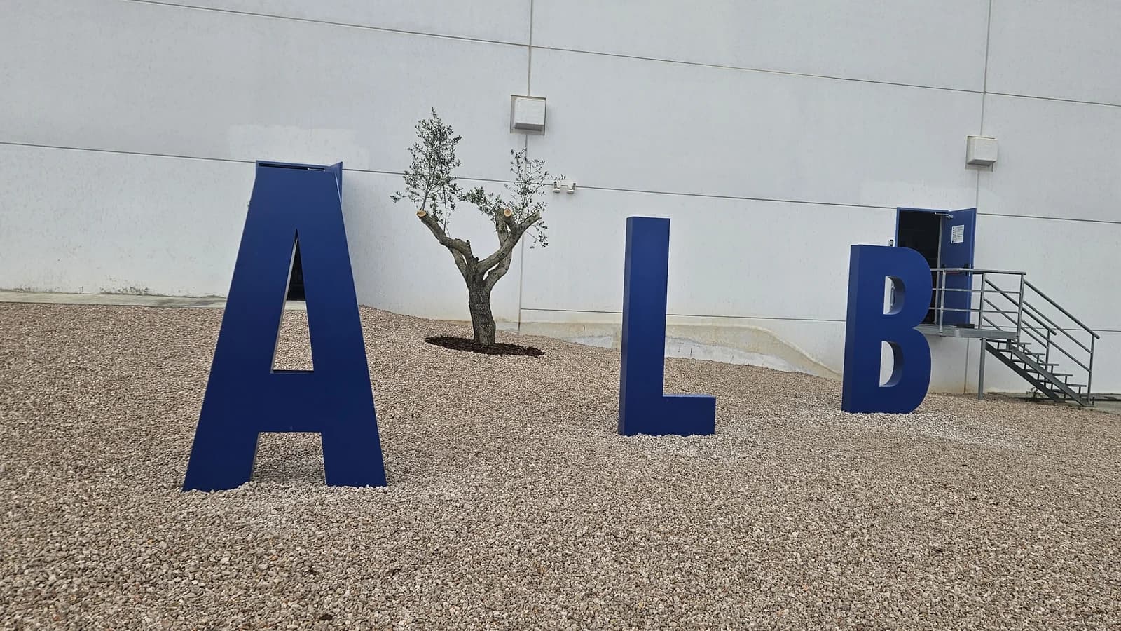 Tres letras corpóreas gigantes ALB de color azul delante de una nave.