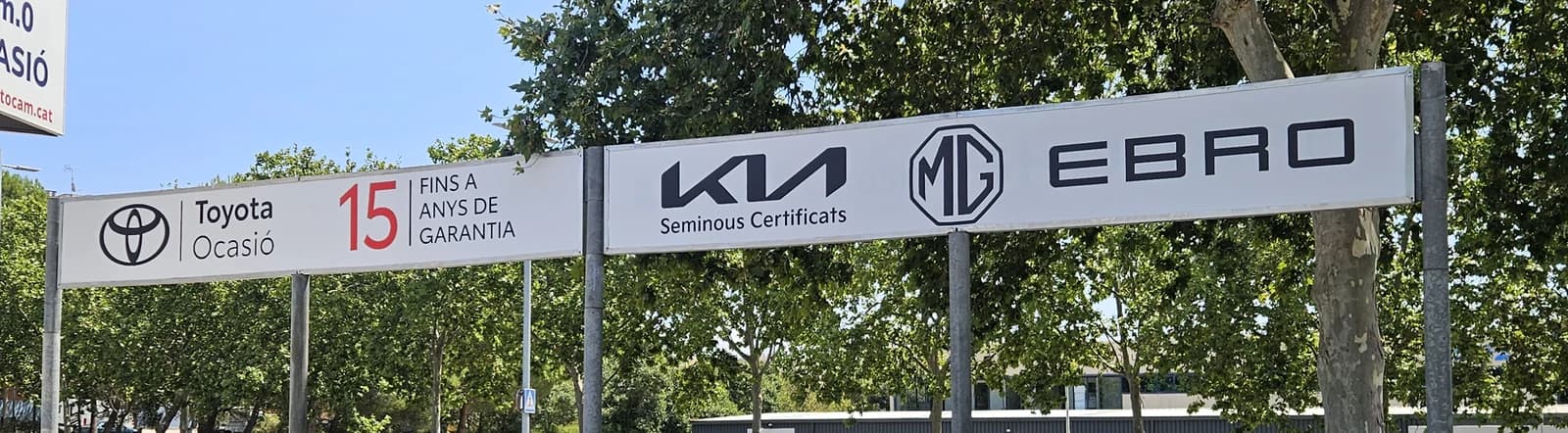 Dos paneles horizontales exteriores con las marcas Toyota, Kia, MG y EBRO sobre soportes.