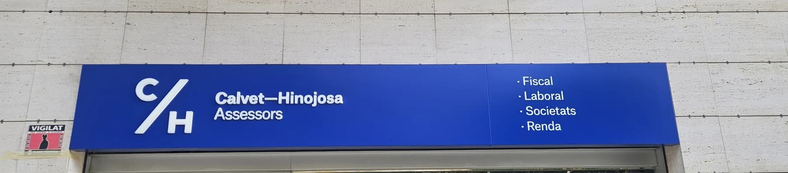 Rótulo azul de Calvet-Hinojosa con el nombre y los servicios, completo en la fachada.