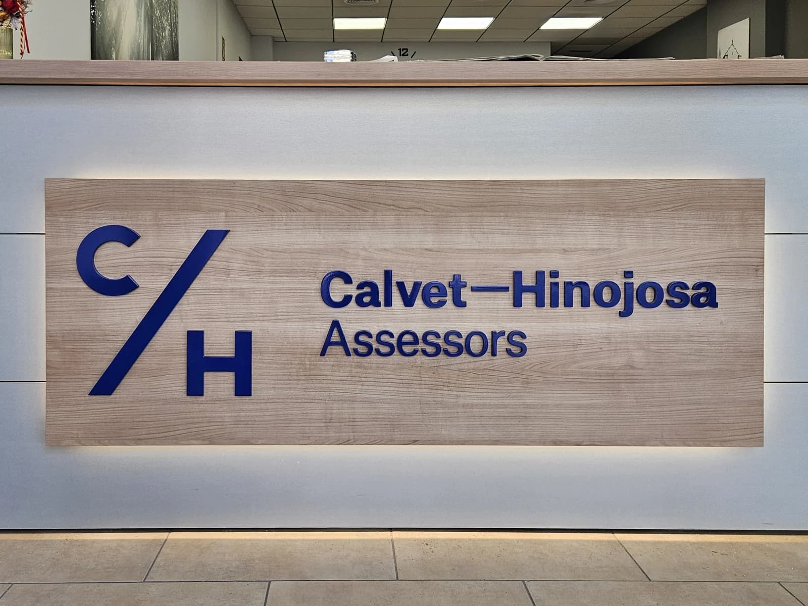 Panel de madera con las letras de Calvet-Hinojosa y luz perimetral.