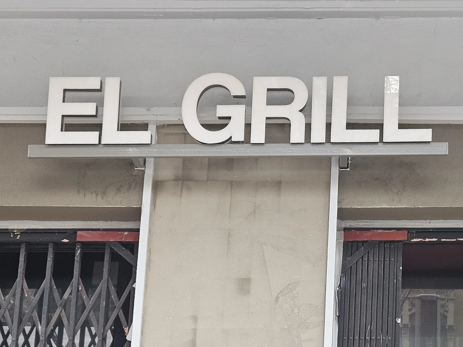 Letras corpóreas blancas de El Grill sobre la puerta del local.