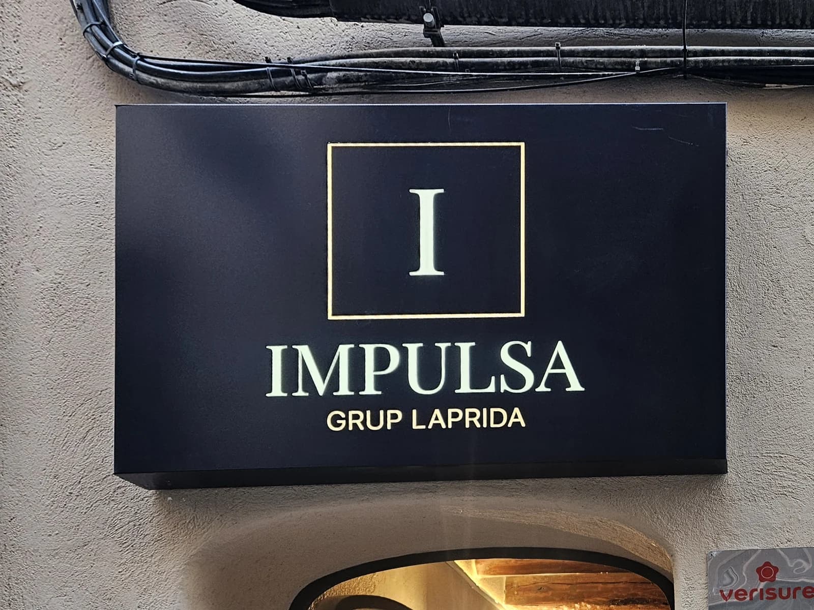 Rótulo rectangular de Impulsa con el símbolo y el nombre en la fachada.