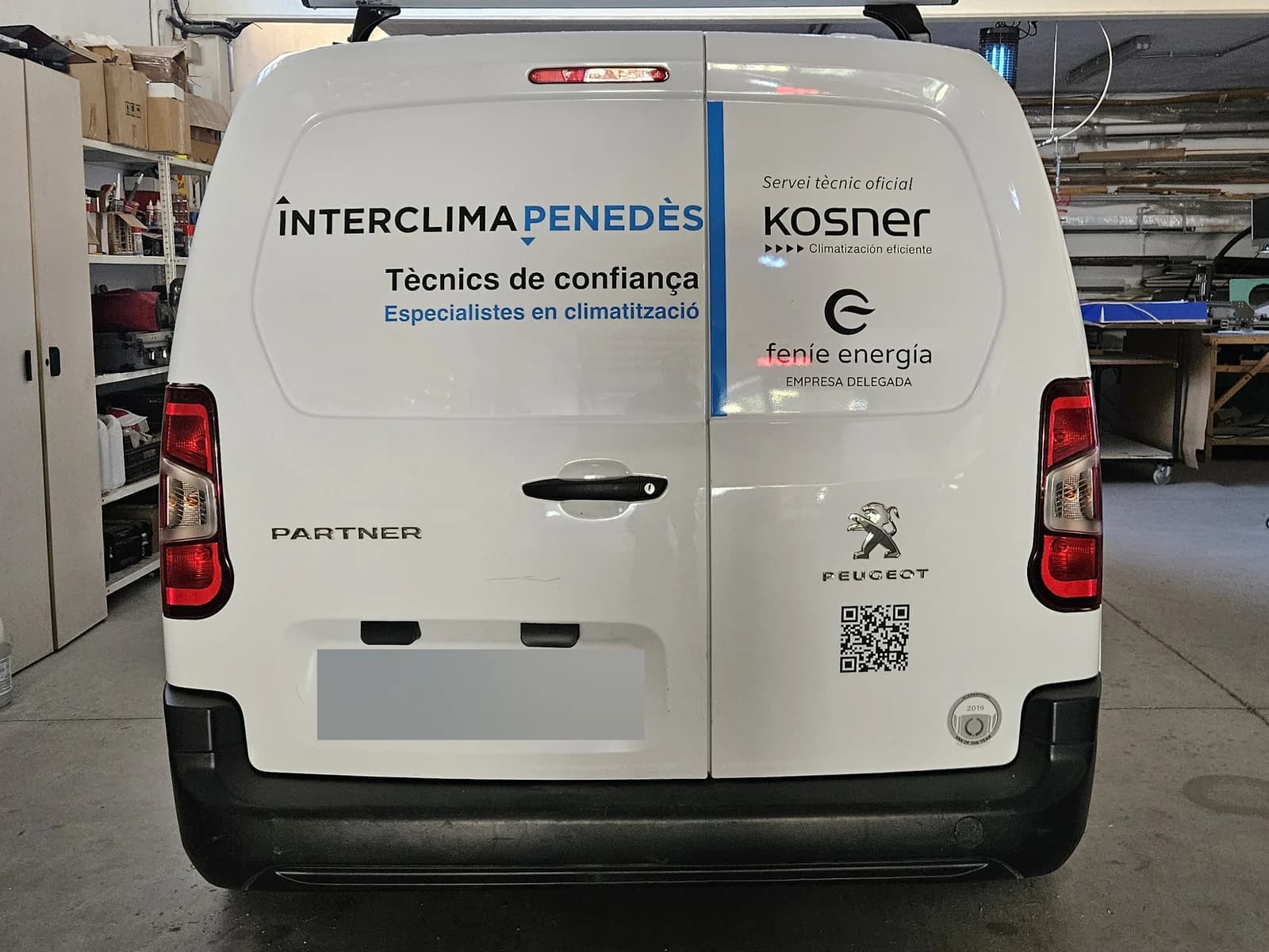 Rotulación de las puertas traseras de una furgoneta de Interclima Penedès en el taller.