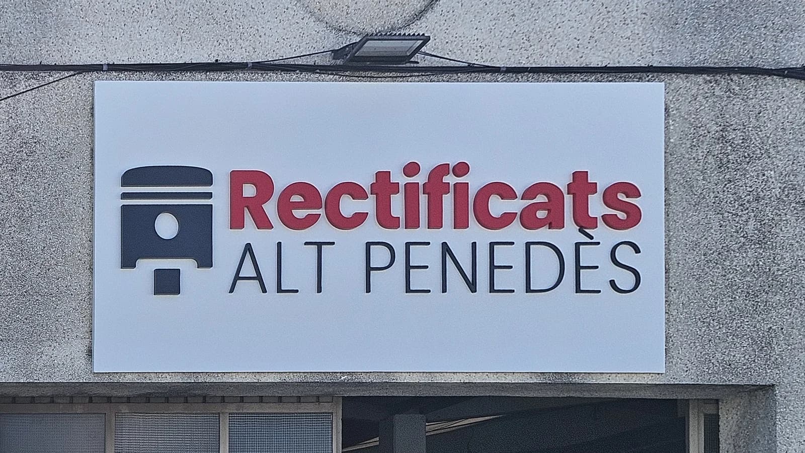 Rótulo de Rectificats Alt Penedès con letras rojas y azules en la fachada.