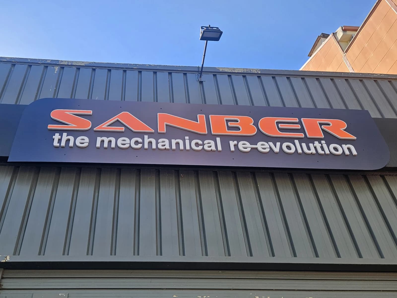 Rótulo de Sanber con el nombre y la actividad sobre la fachada industrial.