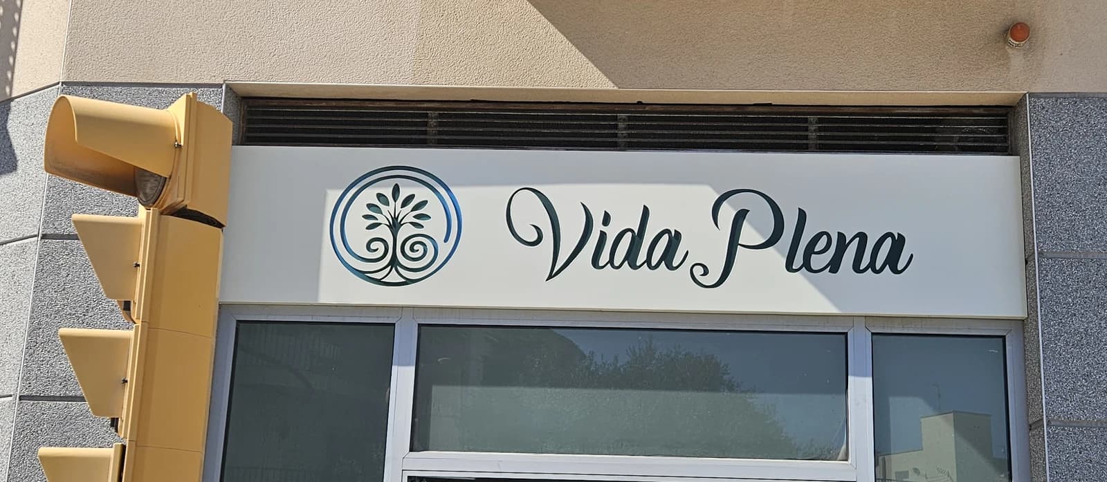 Rótulo de Vida Plena sobre la entrada; a la izquierda se conserva el semáforo de la calle.