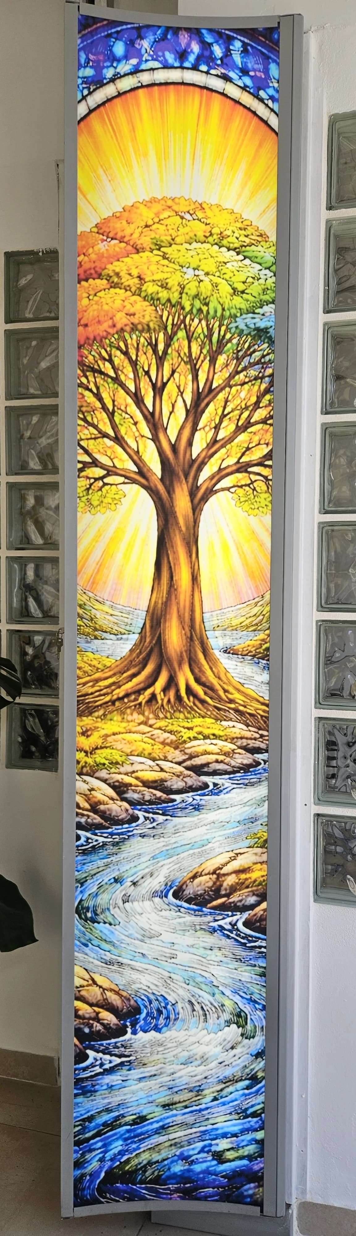 Gráfico vertical de colores con un árbol y un río sobre un cristal interior.