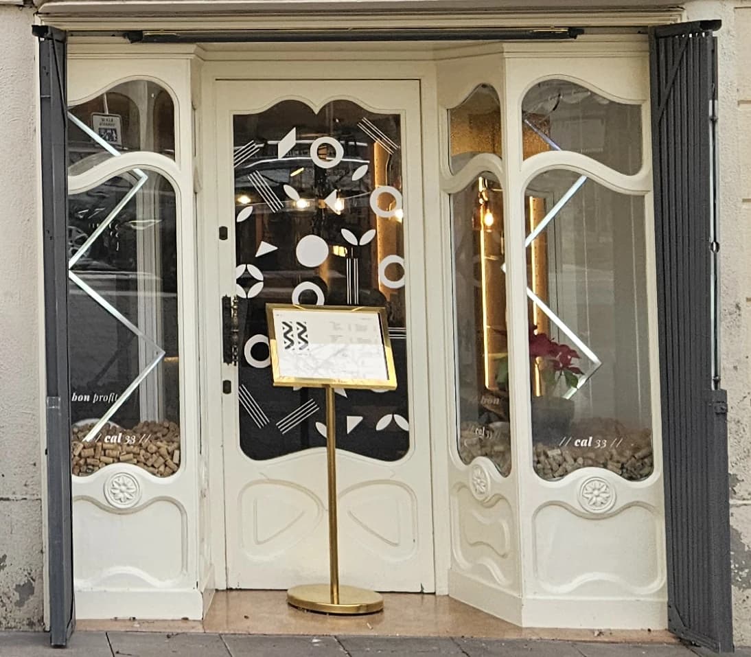Vinilos geométricos blancos sobre las dos hojas de una puerta de cristal.